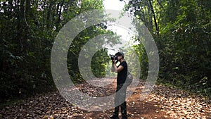 Good looking asian guy standing and take a picture of tropical forest. fresh air.