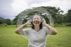 Good-looking asian young woman with no makeup having fun with favorite music outdoor