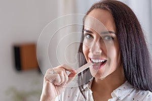 Good-looking brunette puts a chewing gum into her mouth looking into the camera