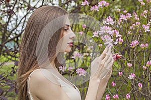 Good-looking brunette woman portrait. Beautiful female model with long hair and make-up in spring garden outdoor