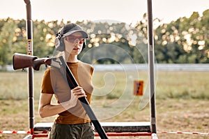 Good-looking caucasian lady with firing gun in outdoor academy shooting range