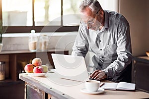 Good-looking enterpreneur working on laptop while having coffee and breakfast