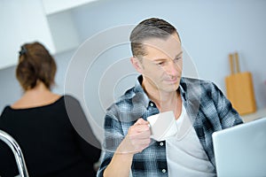 Good-looking enterpreneur working on laptop while having coffee and breakfast photo