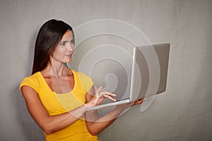 Good-looking female using laptop while standing