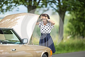 Good looking girl holding her head in hands from desperation after engine failure stopped the car in the nature