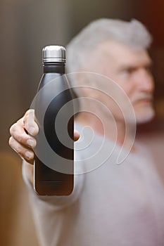 Good looking gray haired senior man in white shirt with water bottle. Sport and health care concept