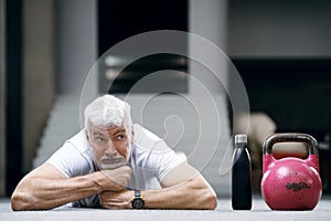 Good looking gray haired senior man in white shirt with water bottle. Sport and health care concept