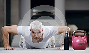 Good looking gray haired senior man in white shirt with water bottle. Sport and health care concept