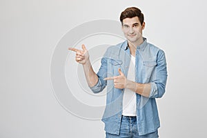 Good-looking handsome european guy with trendy haircut and sincere smile pointing index fingers, doing gun gesture