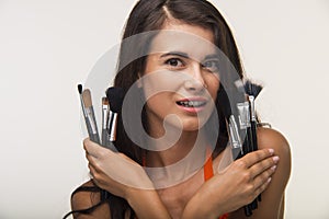 Good-looking lady is showing cosmetic brushes.