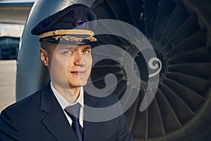 Good-looking male pilot standing by an aeroengine photo
