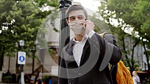 Good looking man in a black suit take his phone and make a call have a conversation he wearing protective mask in