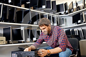 Good looking man enjoying working with system unit