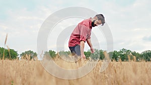 Good looking man farmer concentrated walking in the middle of young wheat field he analyzing the result of work from