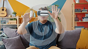 Good-looking man having fun with virtual reality glasses moving hands head
