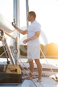 Good-looking man in white tshirt doing something on the yacht