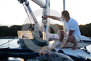 Good-looking man in white tshirt doing something on the yacht