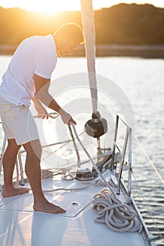 Good-looking man in white tshirt doing something on the yacht