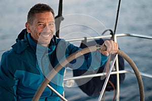 Good-looking mature man sailing a yacht and looking confident