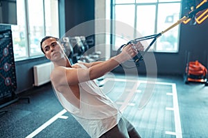 Good looking nice man using trx straps for workout