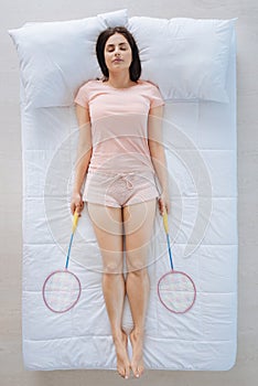 Good looking pleasant woman sleeping with badminton rackets