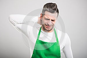 Good looking supermarket employer holding back neck like hurting