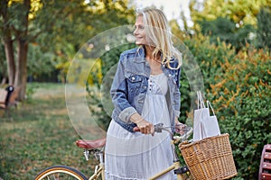 Good looking woman with white shopping bags in basket of vintage bicycle