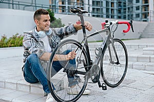 Good-looking young man fixing a problem with a bike tire