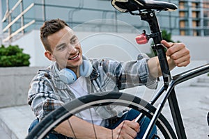 Good-looking young man fixing a problem with a bike tire