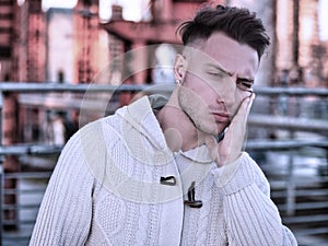 Good looking young man with hand on his face because of tooth-ache