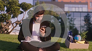 Good looking young man office manager after the end of the day from work he take a sit on the modern park down on the