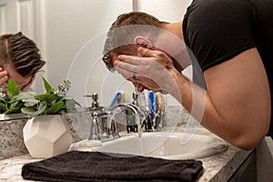 Good Looking Young Man Washing Hands and Face in Home Bathroom Mirror and Sink Getting Clean and Groomed During Morning Routine