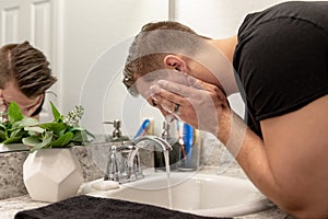 Good Looking Young Man Washing Hands and Face in Home Bathroom Mirror and Sink Getting Clean and Groomed During Morning Routine