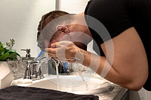 Good Looking Young Man Washing Hands and Face in Home Bathroom Mirror and Sink Getting Clean and Groomed During Morning Routine