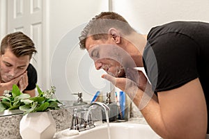 Good Looking Young Man Washing Hands and Face in Home Bathroom Mirror and Sink Getting Clean and Groomed During Morning Routine