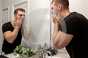 Good Looking Young Man Washing Hands and Face in Home Bathroom Mirror and Sink Getting Clean and Groomed During Morning Routine