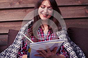 Good-looking young woman smiling while making notes in a jotter