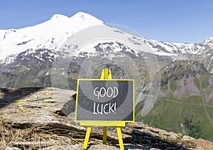 Good luck symbol. Concept words Good luck on beautiful black chalk blackboard. Beautiful mountain Elbrus blue sky background.