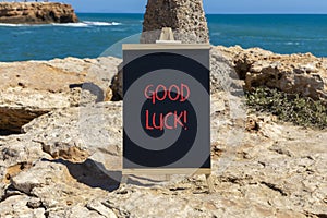 Good luck symbol. Concept words Good luck on beautiful black chalk blackboard. Beautiful stone sea blue sky background. Business,