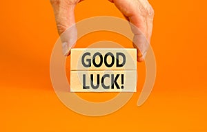 Good luck symbol. Concept words Good luck on beautiful wooden block. Beautiful orange table orange background. Businessman hand.