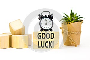 Good luck symbol. Concept words Good luck on beautiful wooden block. Beautiful white table white background. Black alarm clock.