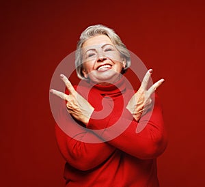 Good mood happy smiling positive elderly woman show v-sign isolated over red background