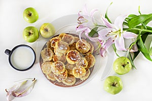 Good morning, breakfast with cheese cakes and milk and apples on a table lit by the sun, horizontal