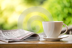 good morning coffee cup with news paper on nature green background in garden