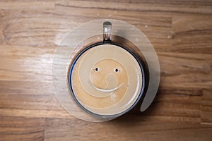 Good morning coffee smile cup on wooden background. Cup of delicious hot coffee with foam and smile on color background