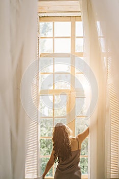 Good morning mood. Woman opening window. View from back