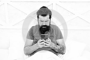 Good morning SMS. Bearded man texting sms in bed. Hipster send sms using smartphone. Sms message. Short message service