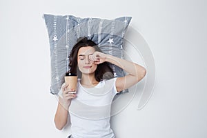 Good morning. Young woman drinking coffee with a pillow under her head,