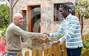 Good neighbors talk on the border of their farms