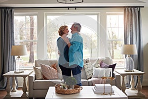 Good old fashioned romance is timeless. a happy mature couple dancing together in their living room at home.